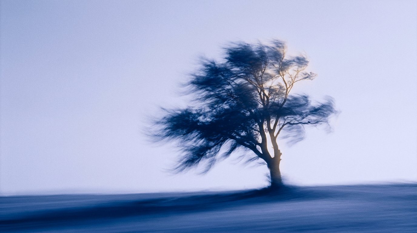 Baum im Wind vor blauem Himmel