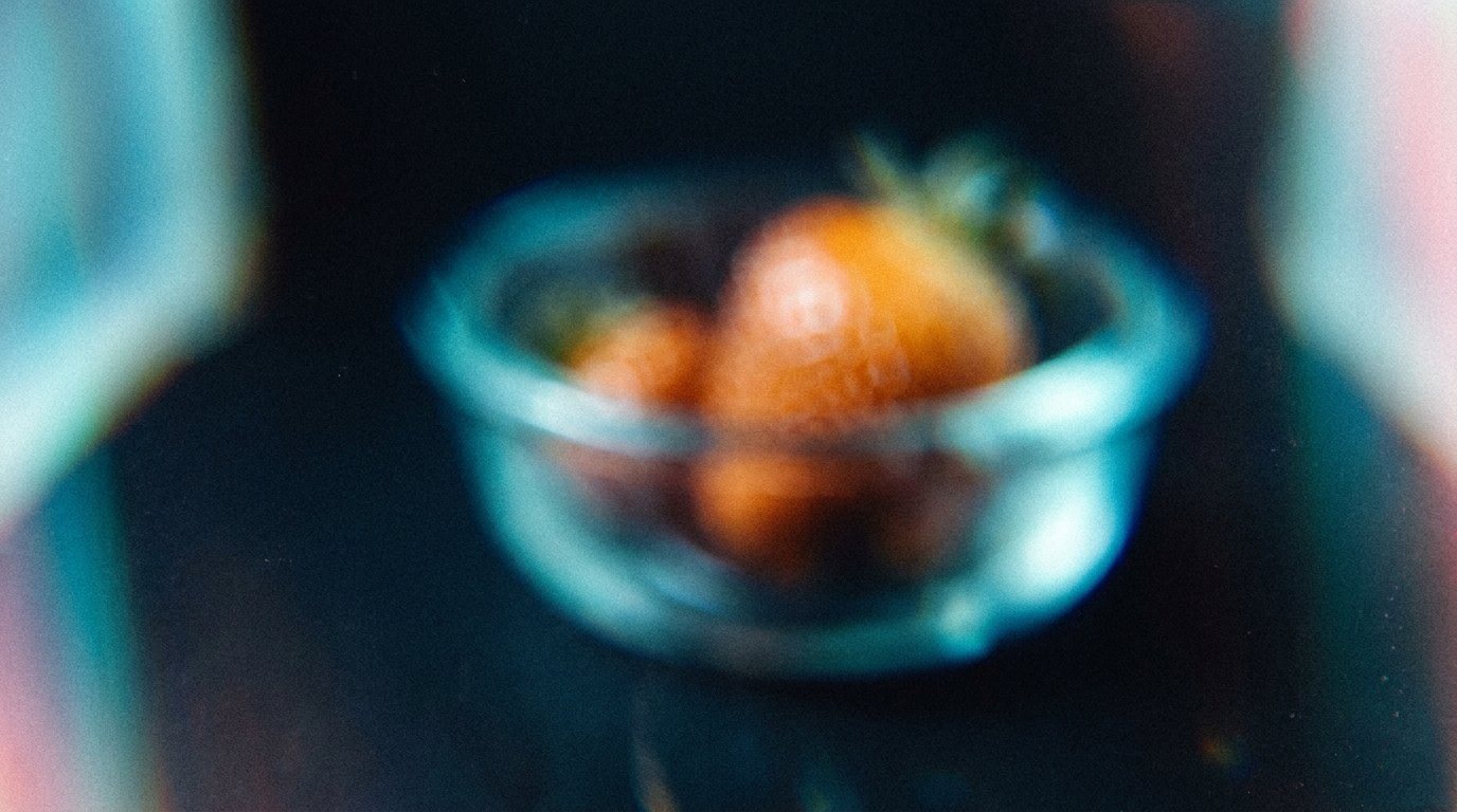 Unscharfe Glasschale mit Erdbeeren auf dunklem Grund